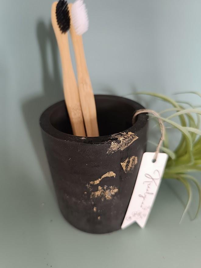 Pot rangement brosses à dents noir et or.